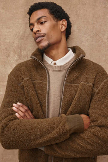 The Clark is a zip front brushed back polar fleece and details include contrast stitching, two zipper pockets, and contrast  grey ribbed cuffs in Lichen colorway. Front detail view featured on model.