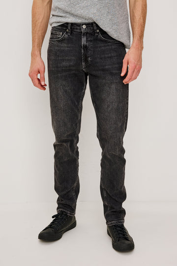 Clayton Slim Straight is a Classic 5-Pocket Jean in Faded Onyx Colorway, a Washed Black. Front View Featured on Model.