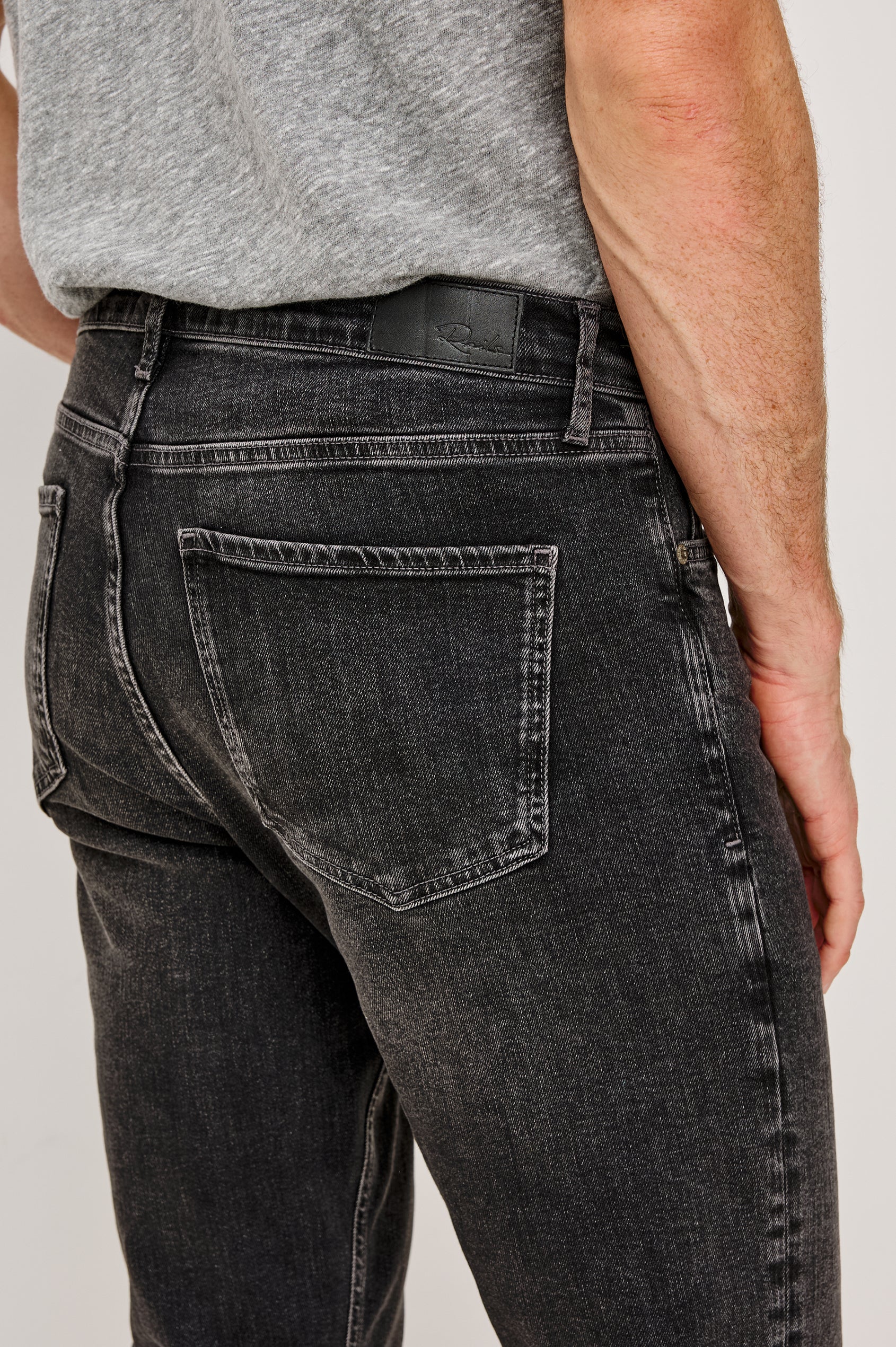 Clayton Slim Straight Jean With 5-Pocket Styling, Belt Loops, and Front Zip-Fly in Faded Onyx Black Colorway - Lower Body Back Close Up View Featured on Model