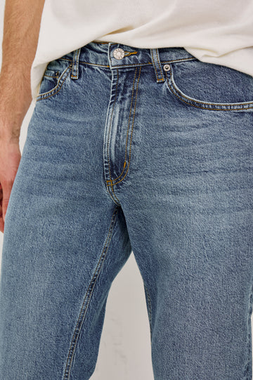 Clayton Slim Straight is a Classic 5-Pocket Jean in Heritage Indigo Colorway, a Medium Blue Wash. Front Detail View Featured on Model.