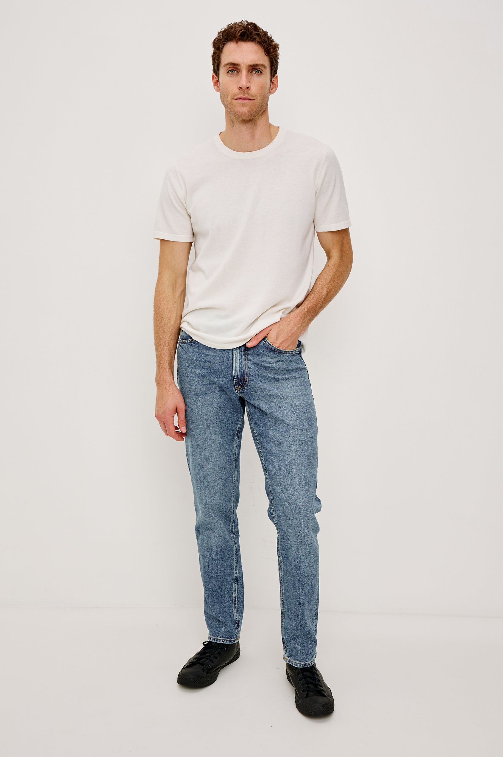 Clayton Slim Straight is a Classic 5-Pocket Jean in Heritage Indigo Colorway, a Medium Blue Wash. Front Full Body View Featured on Model.