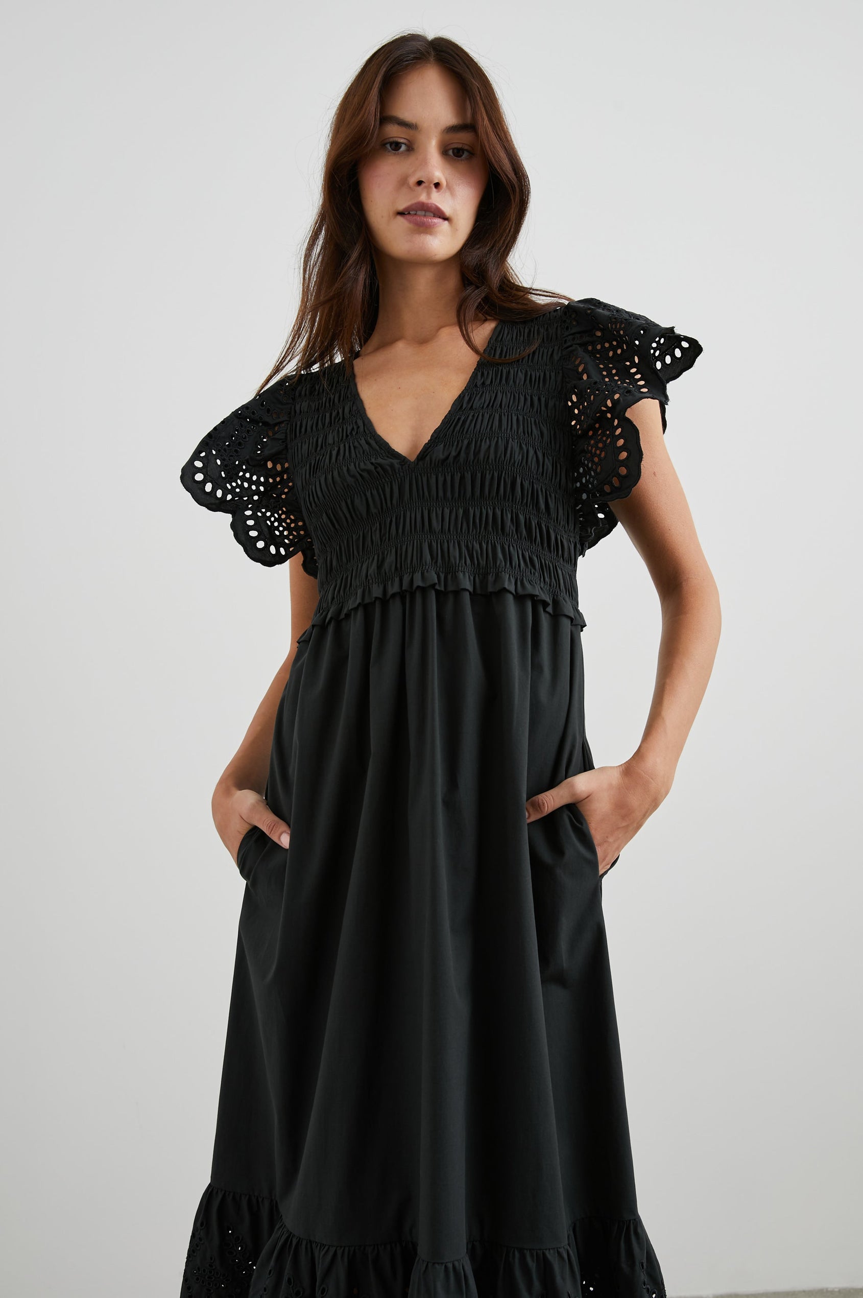 Clementine Midi Dress with a Deep V Neckline, Flutter Sleeves, Smocked Top, Two Side Pockets and eyelets on the Sleeves and Hem in Black Eyelet Colorway- Front View Featured on Model
