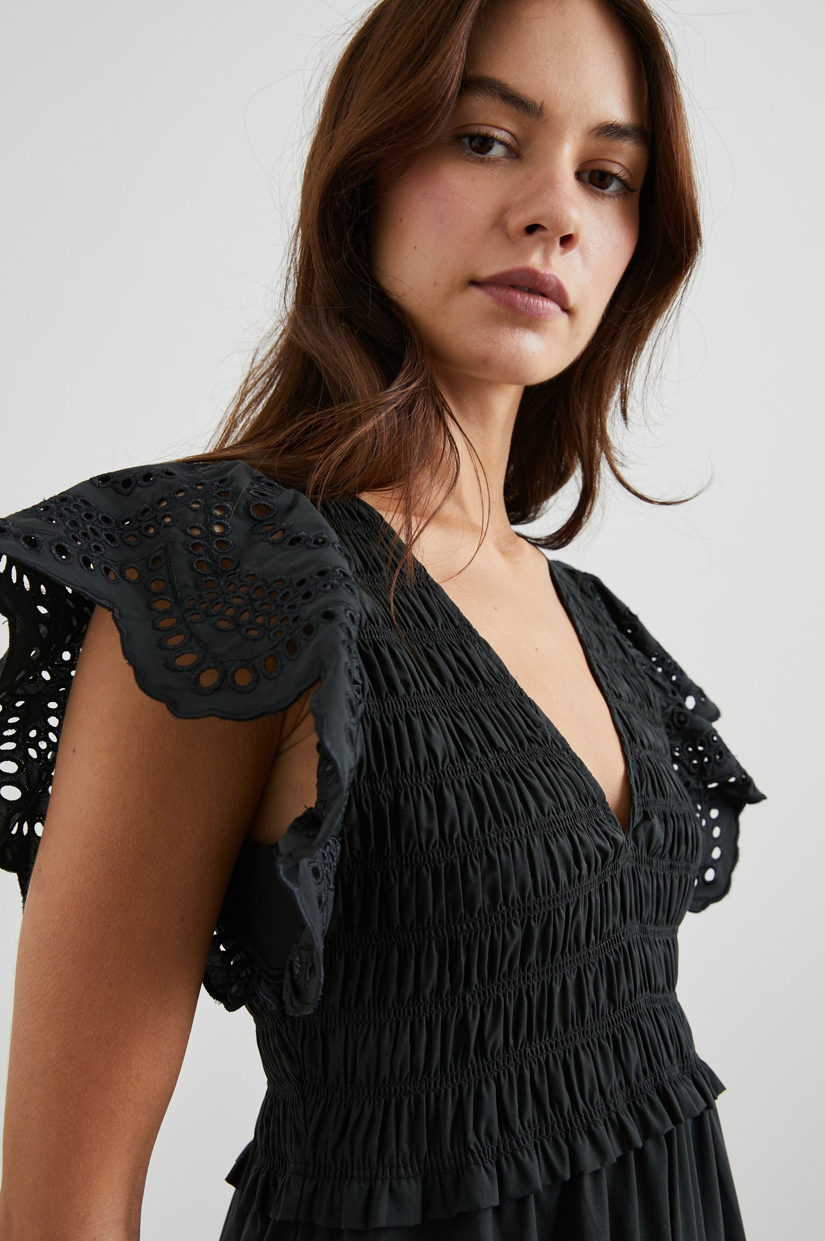 Clementine Midi Dress with a Deep V Neckline, Flutter Sleeves, Smocked Top, Two Side Pockets and eyelets on the Sleeves and Hem in Black Eyelet Colorway- Side View Featured on Model