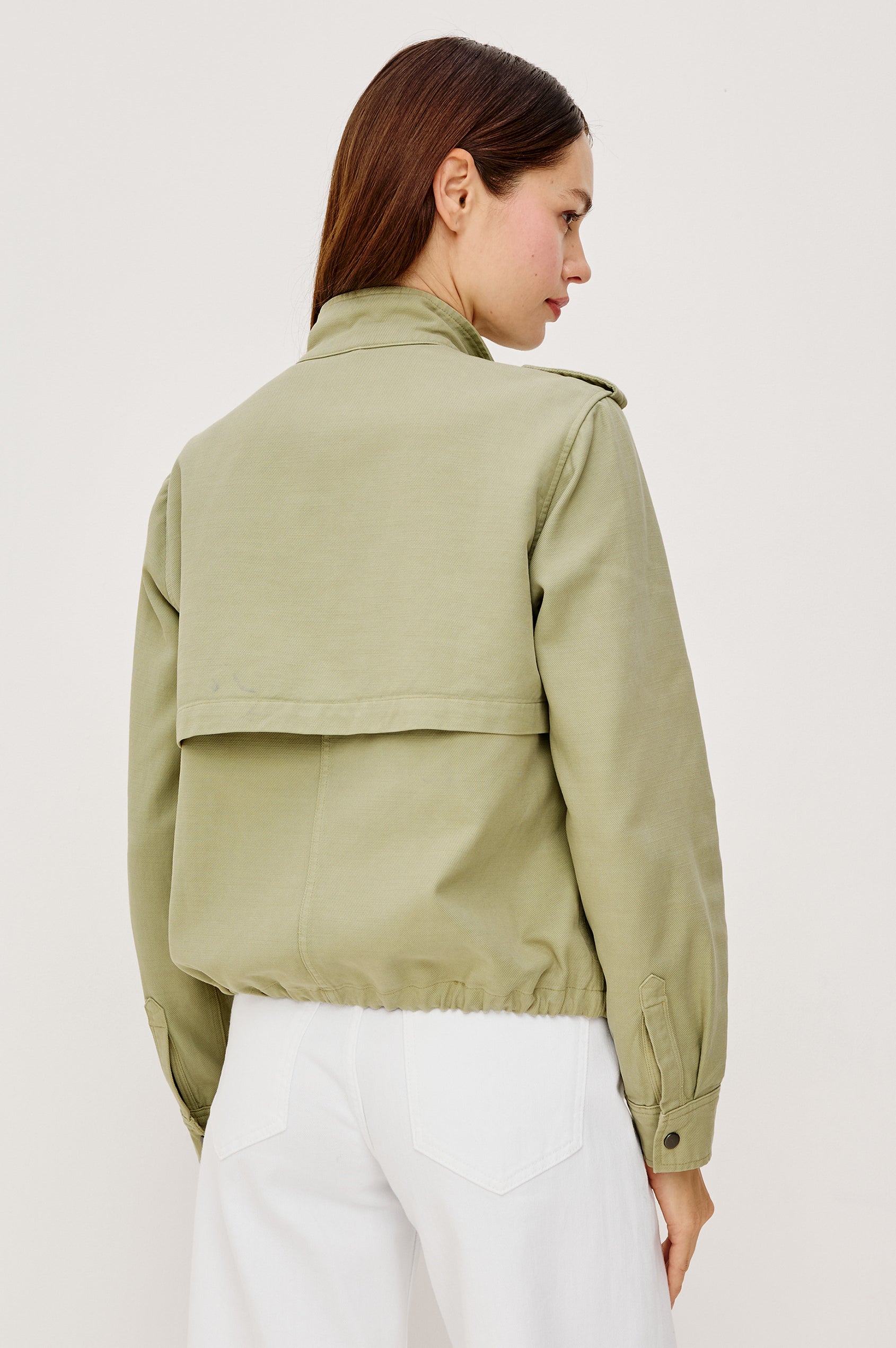 Collins Miitary Inspired Jacket With Shoulder Epaluettes Stand Collar Front Snap Buttons Double Chest Pockets Long Sleeves in Vintage Sage Colorway - Upper Body Front View Featuered on Model