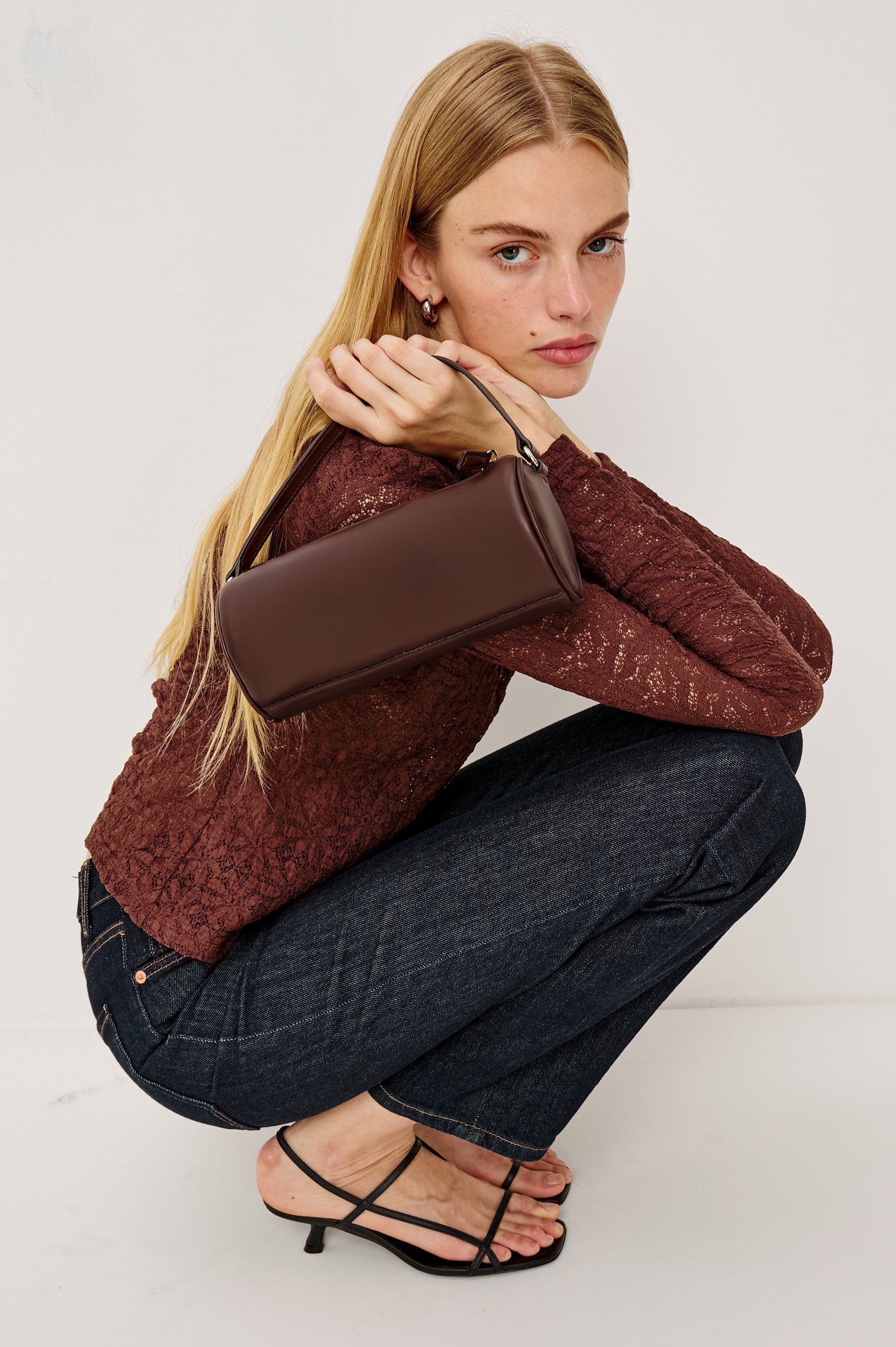 Como Mini Barrel Bag in Italian Leather With Fixed Top Strap, Removable and Adjustable Buckled Crossbody Strap, Top Zipper, Side-Embossed Logo, Branded Interior Label in Espresso Colorway - Stylized Model Featured