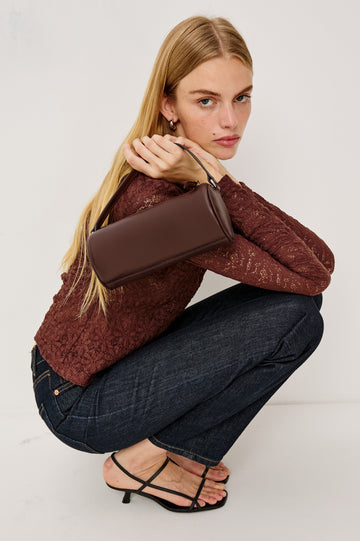 The Como is a mini barrel bag, made from smooth leather with a fixed top strap, a removable and adjustable buckled crossbody strap, a top zip, a side-embossed logo, and a branded interior label, in Espresso colorway. Front full body view featured on model.