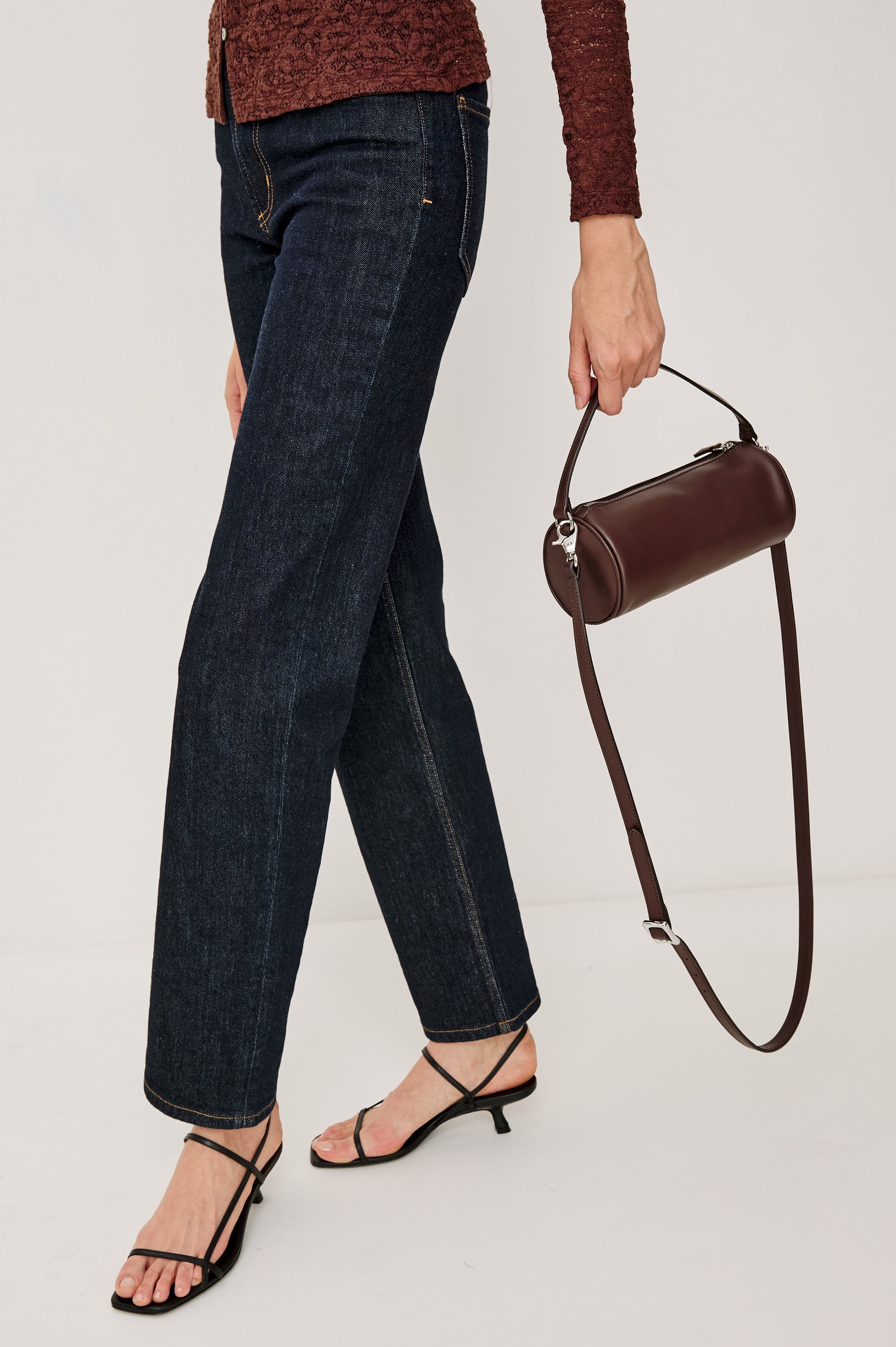 Como Mini Barrel Bag in Italian Leather With Fixed Top Strap, Removable and Adjustable Buckled Crossbody Strap, Top Zipper, Side-Embossed Logo, Branded Interior Label in Espresso Colorway - Stylized Model Featured