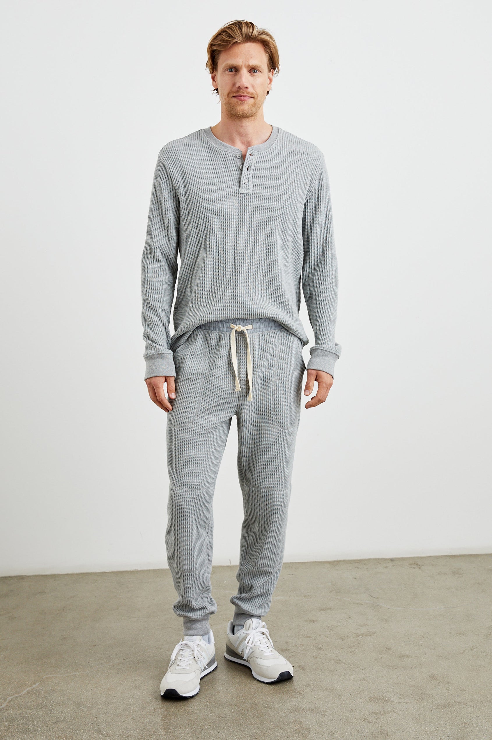 Cooper Waffle Thermal Pants with an Elastic Drawstring Waist, Two Teardrop Front Pockets, Two Back Welt Pockets, Reinforced Knee Patches and Elastic Cuffs in Heather Grey Colorway - Front Full Body View Featured on Model