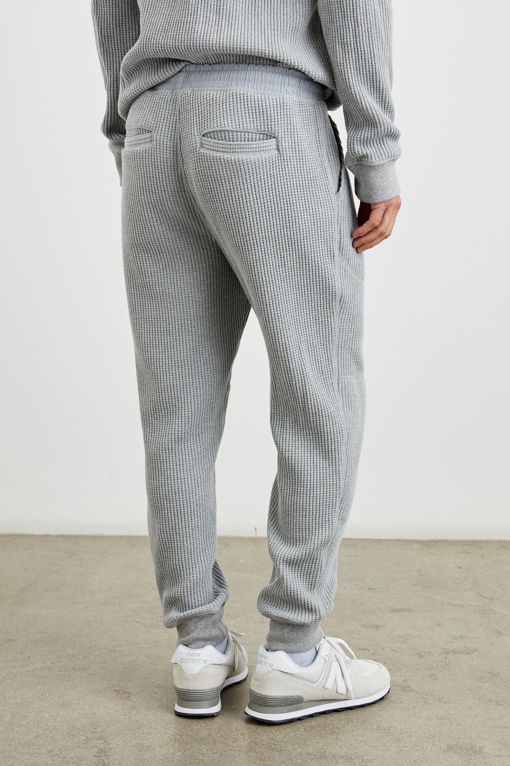 Cooper Waffle Thermal Pants with an Elastic Drawstring Waist, Two Teardrop Front Pockets, Two Back Welt Pockets, Reinforced Knee Patches and Elastic Cuffs in Heather Grey Colorway - Back View Featured on Model