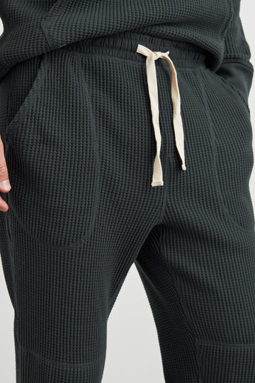 Cooper Waffle Thermal Pants with an Elastic Drawstring Waist, Two Teardrop Front Pockets, Two Back Welt Pockets, Reinforced Knee Patches and Elastic Cuffs in Ink Colorway - Front View Featured on Model