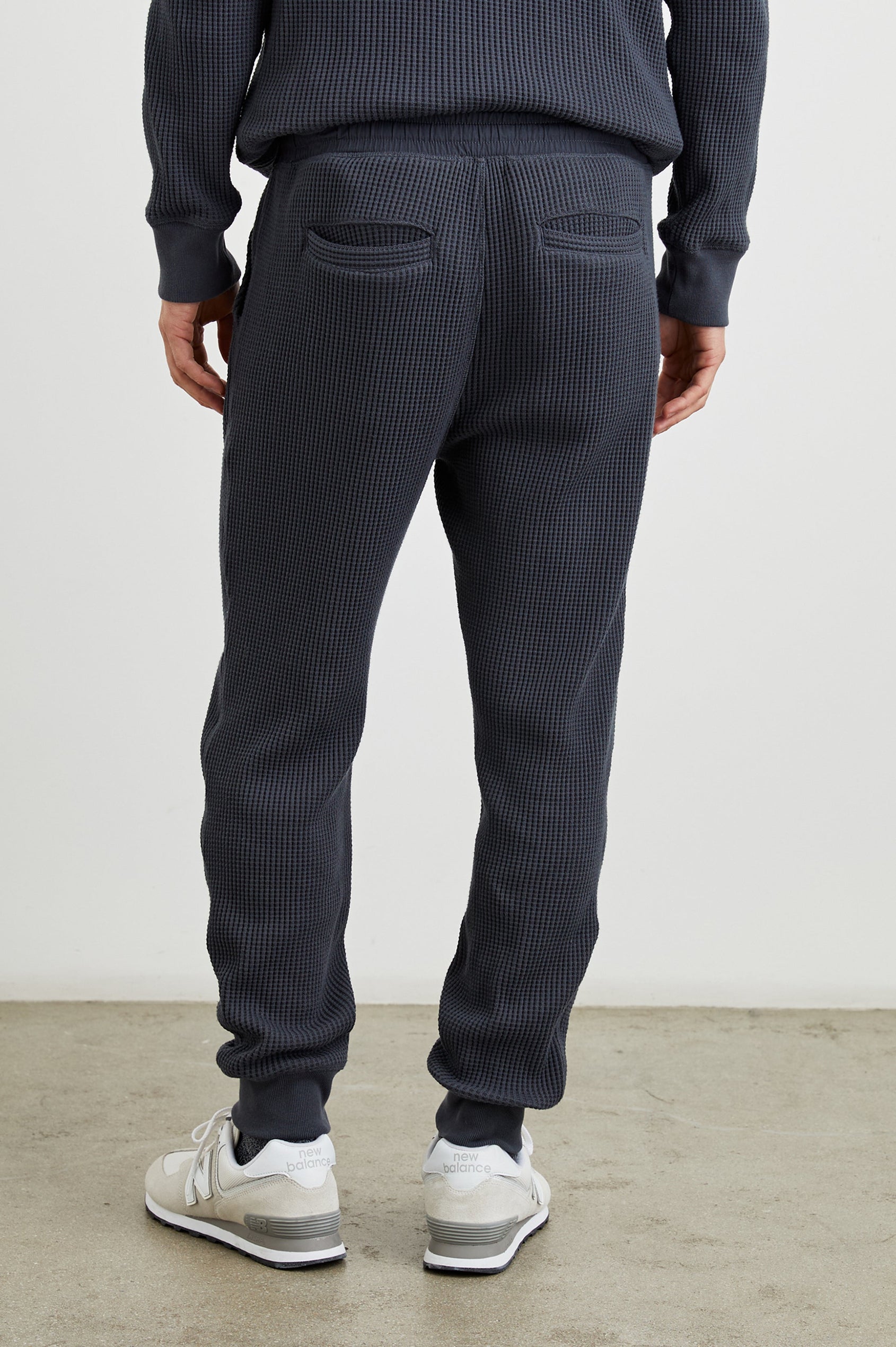 Cooper Waffle Thermal Pants with an Elastic Drawstring Waist, Two Teardrop Front Pockets, Two Back Welt Pockets, Reinforced Knee Patches and Elastic Cuffs in Ink Colorway - Back View Featured on Model