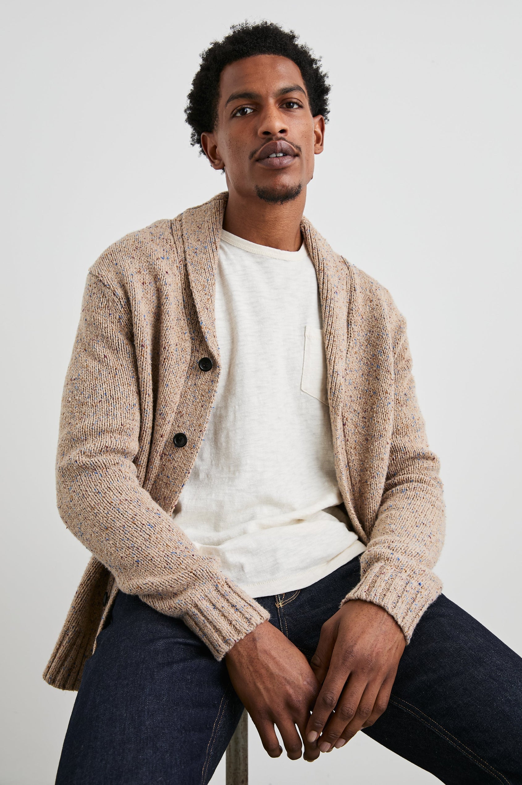 Corden Long-Sleeve Cardigan with Button Closure, a Shawl Collar and Ribbed Trim in Oatmeal Speckle Colorway - Front View Featured on Seated Model