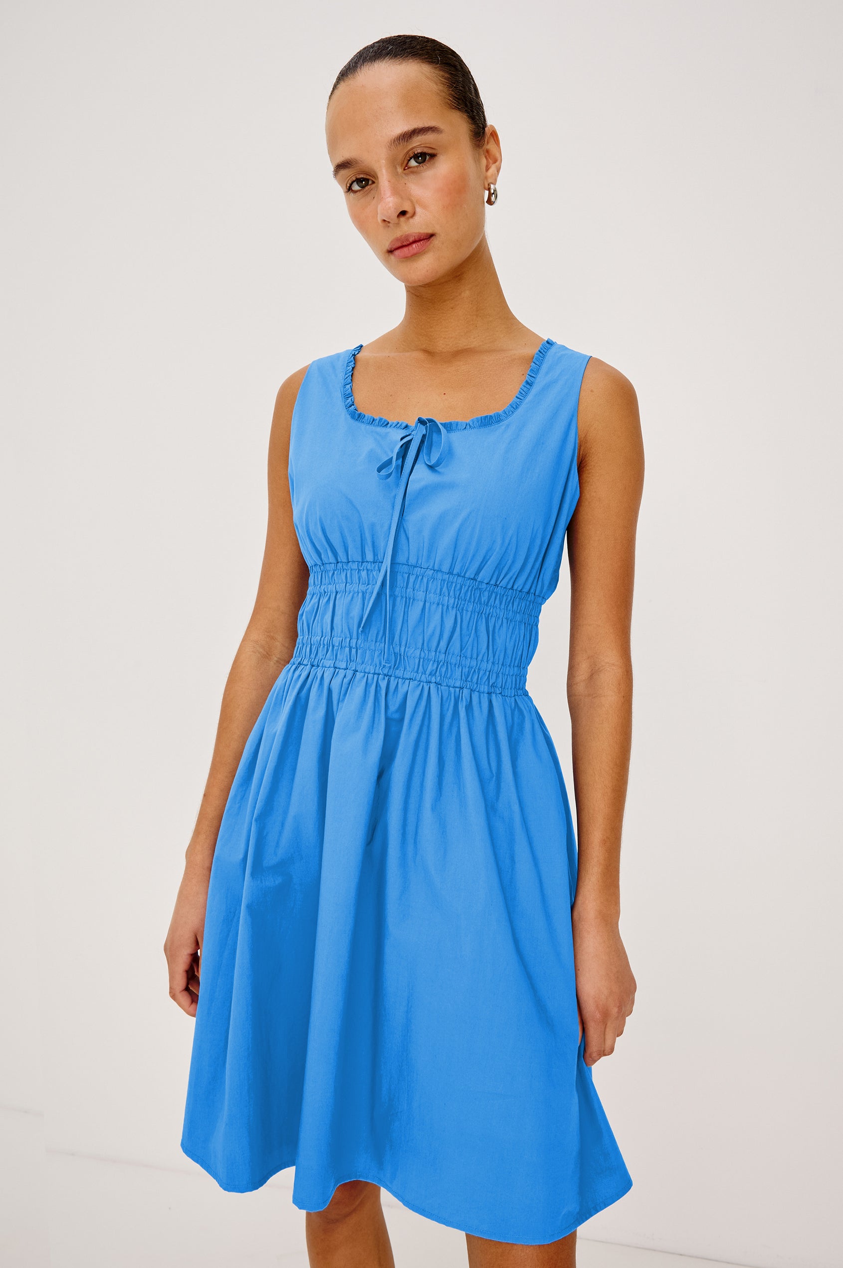 Cosette Mini Dress in Cotton Poplin With Square Neckline, Center Bust Ties, Ruffle Trim, and Smocked Waist in Harbor Blue Colorway - Upper Body View Featured on Model