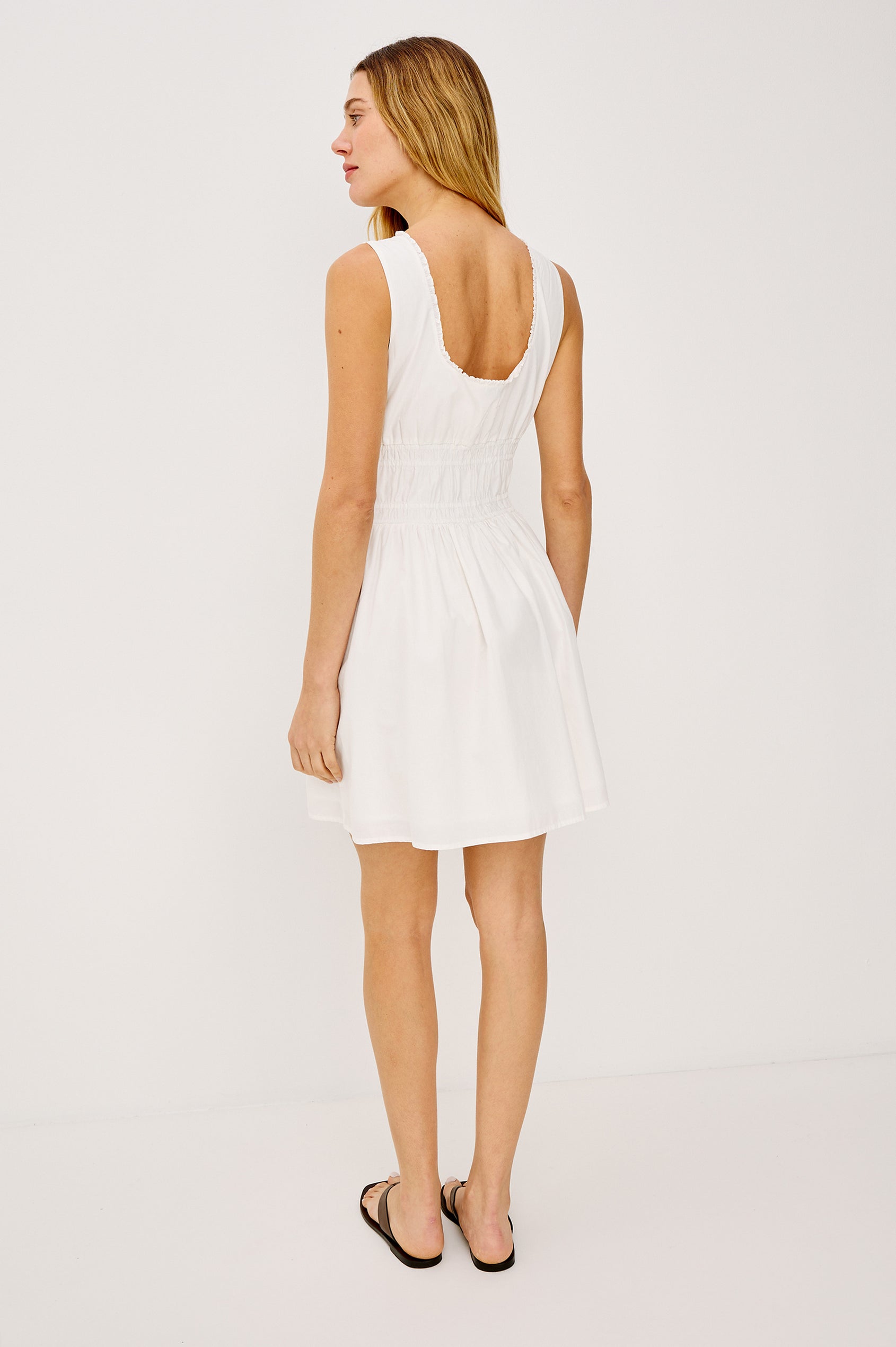 Cosette Mini Dress in Cotton Poplin With Soft Square Neckline, Center-Front Bust Ties, Smocked Waist, Side Pockets, and A-Line Skirt in White Colorway - Full Body Back View Featured on Model