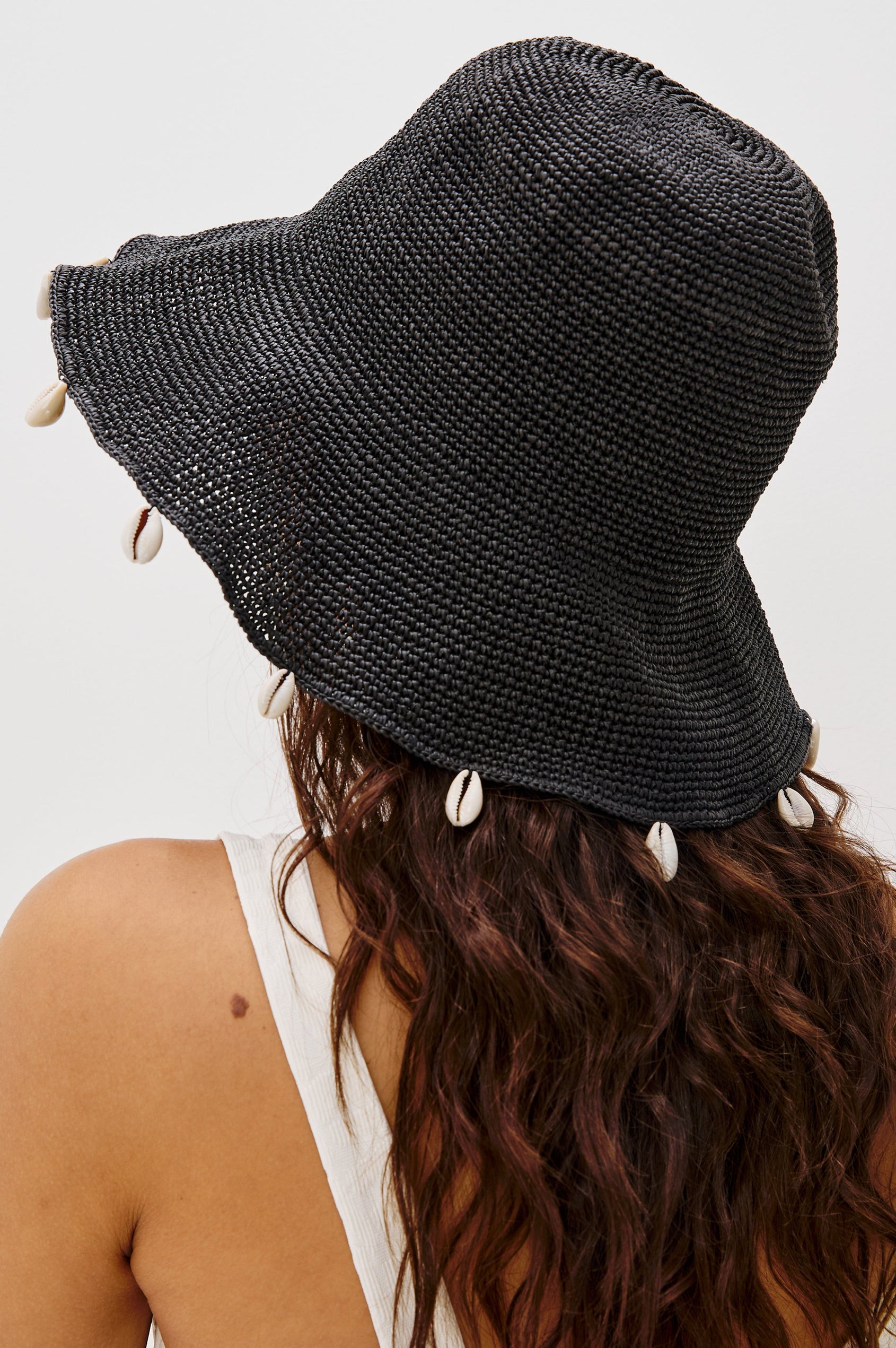 Crete Rattan Wide Brim Hat with Hanging Sea Shells at Edge in Black Colorway. Back Detailed View Shown on Model.
