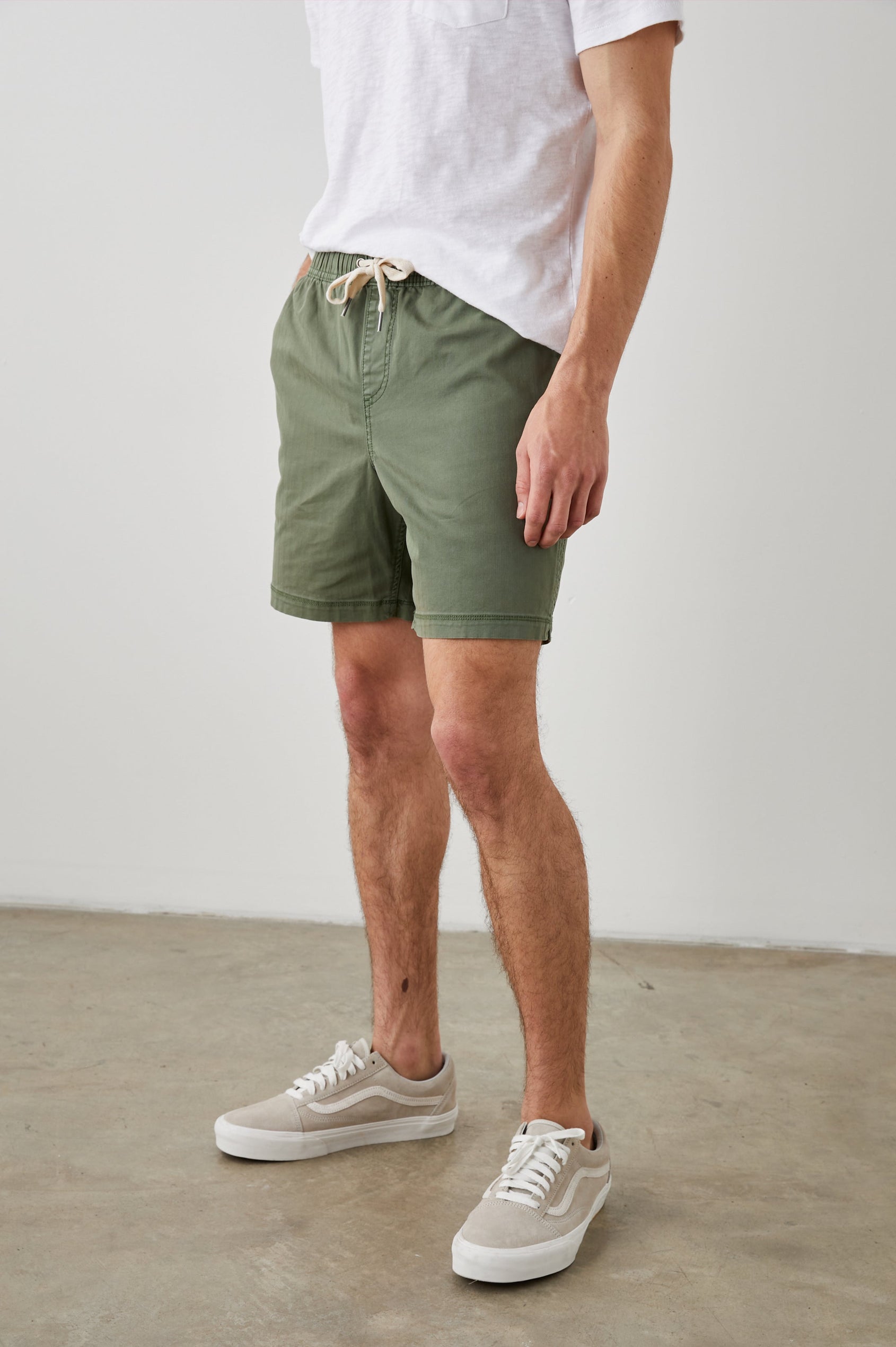 Cruz Shorts with a Drawstring Waist, Two Front Pockets, Two Back Button Flap Pockets in Spring Olive Colorway - Side View Featured on Model 