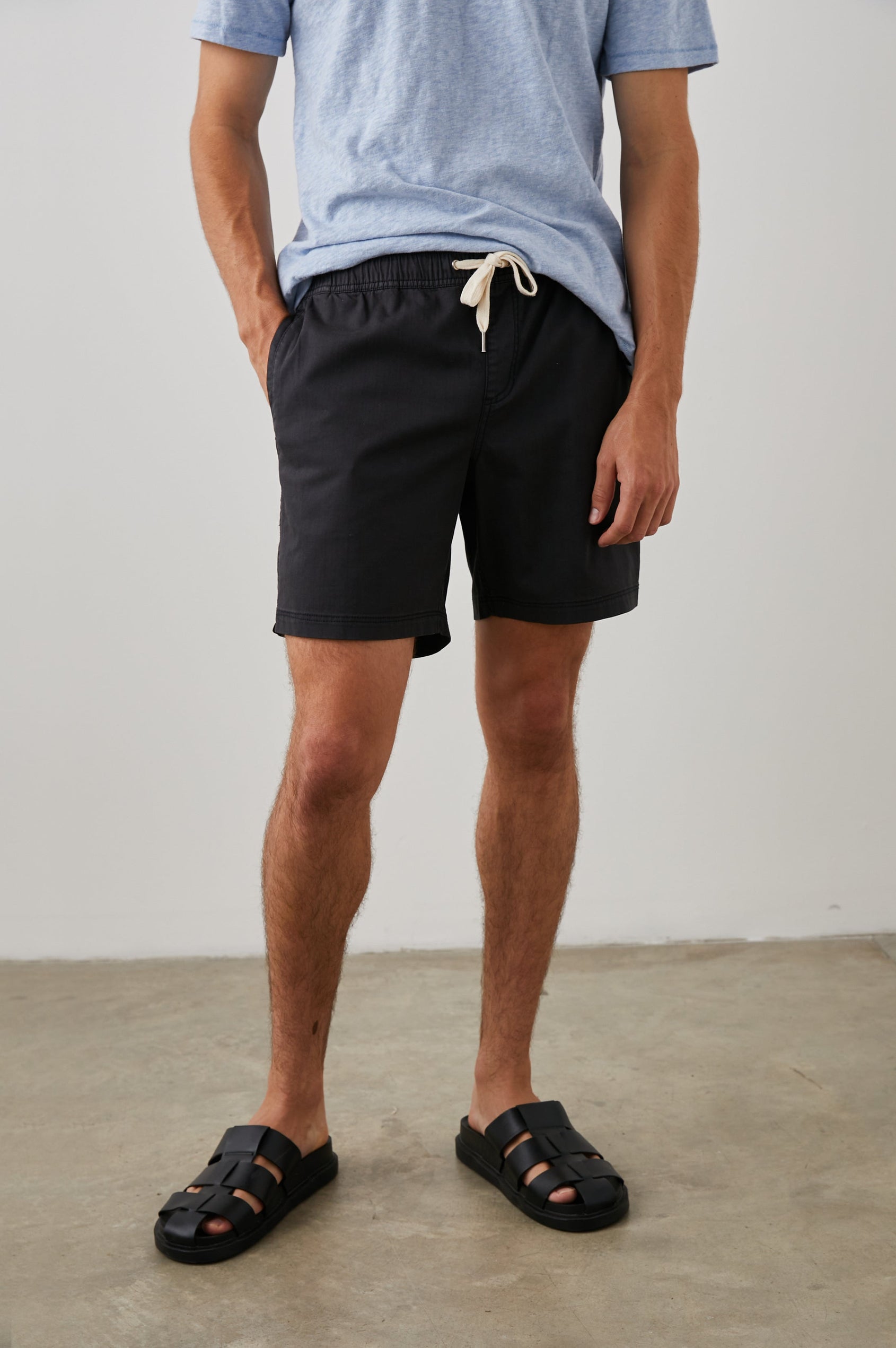 Cruz Shorts with a Drawstring Waist, Two Front Pockets, Two Back Button Flap Pockets in Washed Black Colorway - Front View Featured on Model 