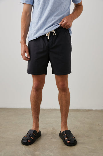 Cruz Shorts with a Drawstring Waist, Two Front Pockets, Two Back Button Flap Pockets in Washed Black Colorway - Front View Featured on Model 
