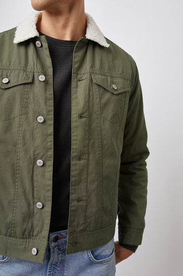 McKinley Jacket with Button Closure, Two Chest Button Flap Pockets, Two Front Pockets and a Cream Faux Sherpa Collar in Olive Colorway - Front View Featured on Model