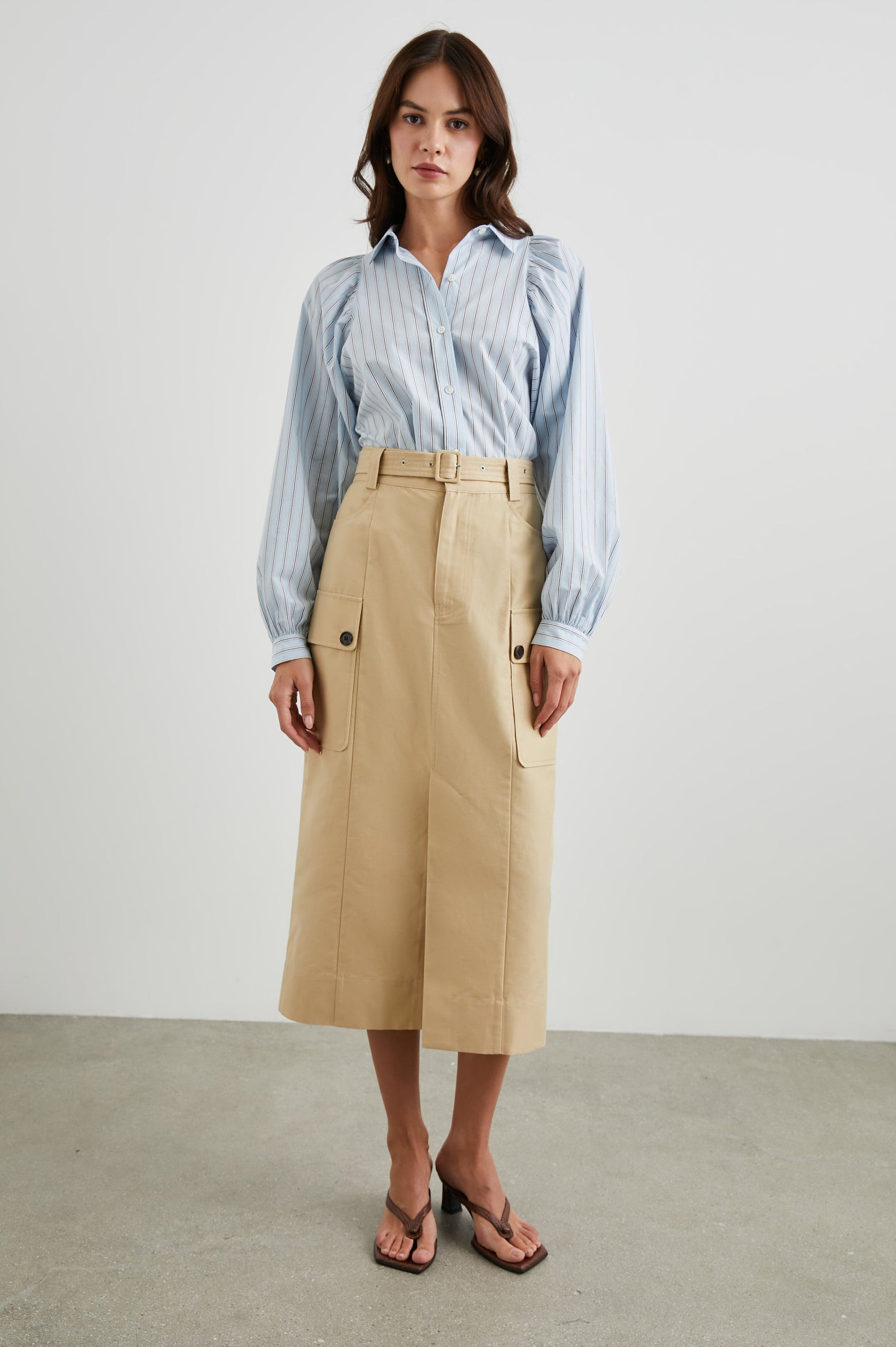Cyrus Midi Skirt with a Center Slit, Belt Loops, a Fabric Belt, Two Front Pockets and Two Side Button Flap Pockets in Khaki Colorway, with Dark Buttons - Front Full Body View Featured on Model 