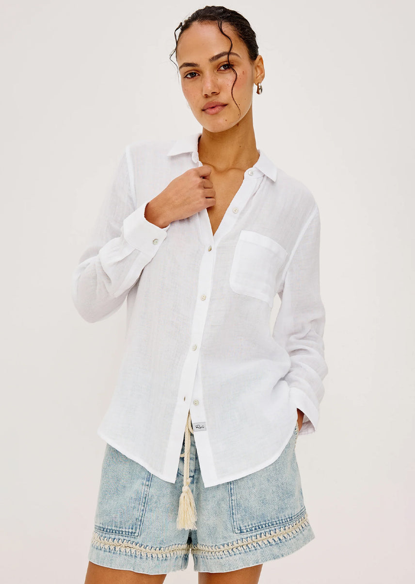 Woman wearing a white shirt and denim shorts on a plain background