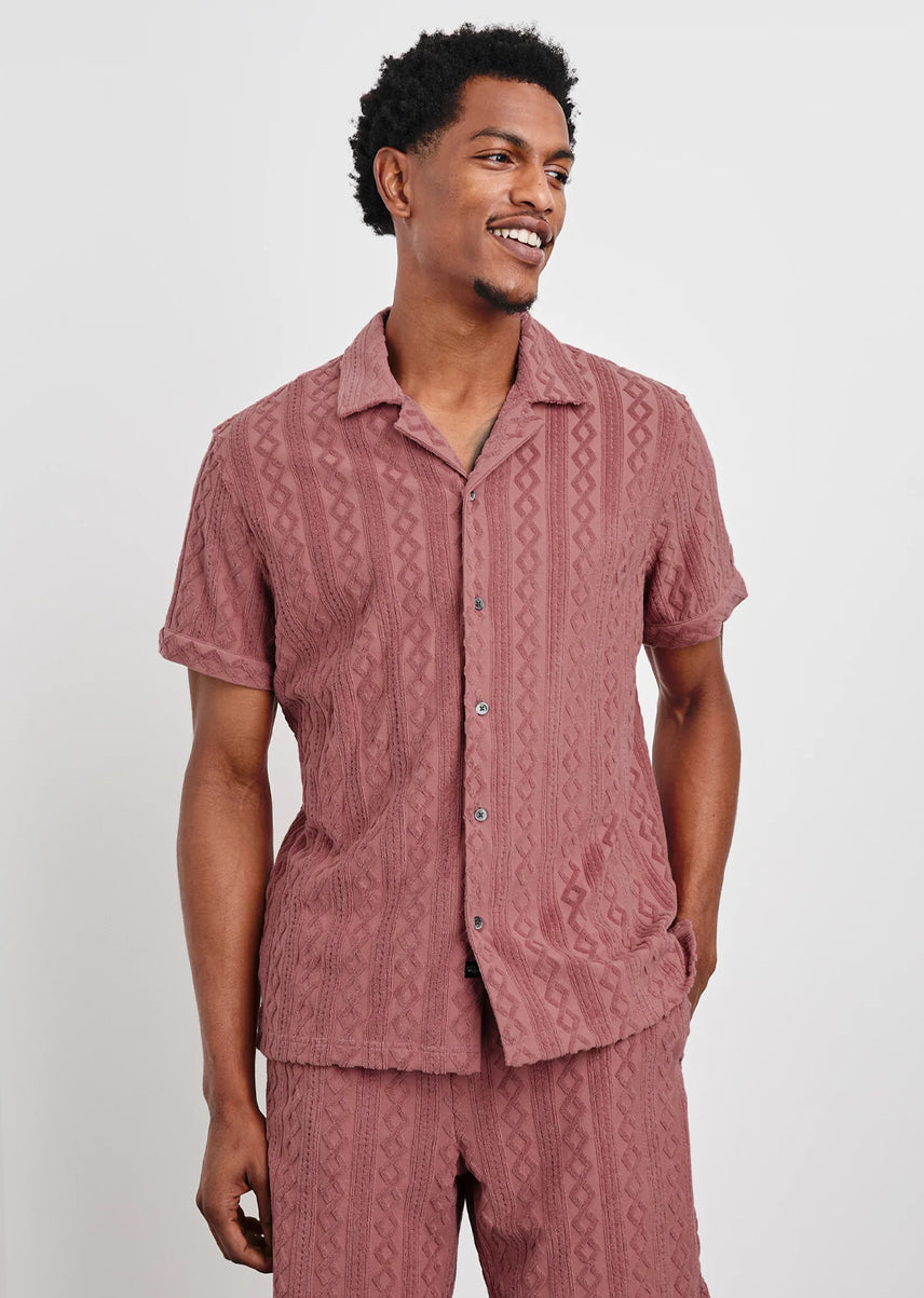 Man wearing a matching pink shirt and pants set on a white background