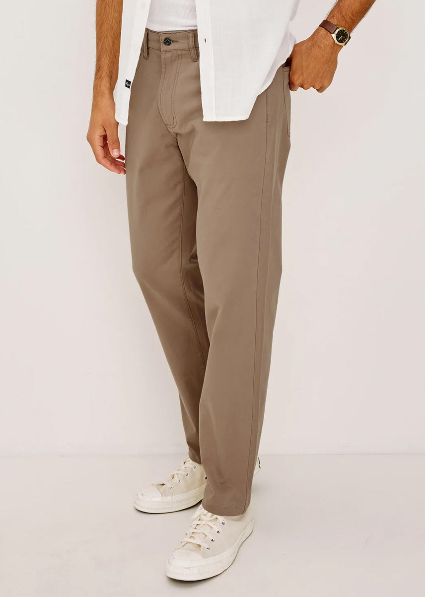 Person wearing beige pants and white sneakers on a plain background