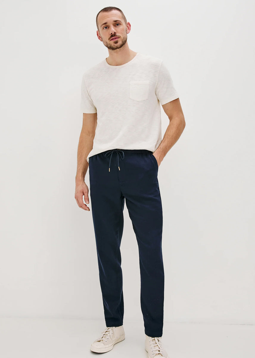 Man wearing a white t-shirt and blue pants against a white background