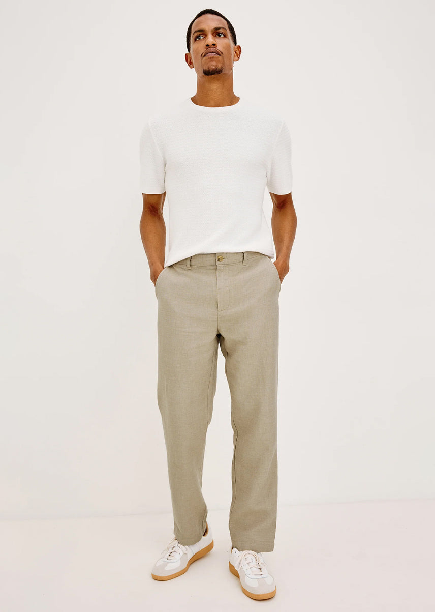 Man wearing a white t-shirt and beige pants on a white background