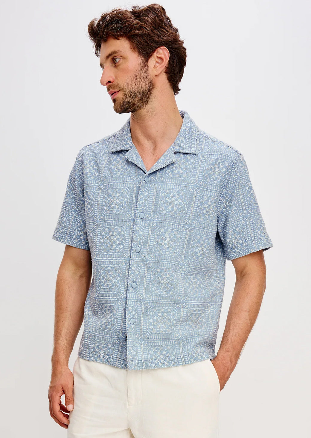 Man wearing a blue patterned shirt against a light gray background