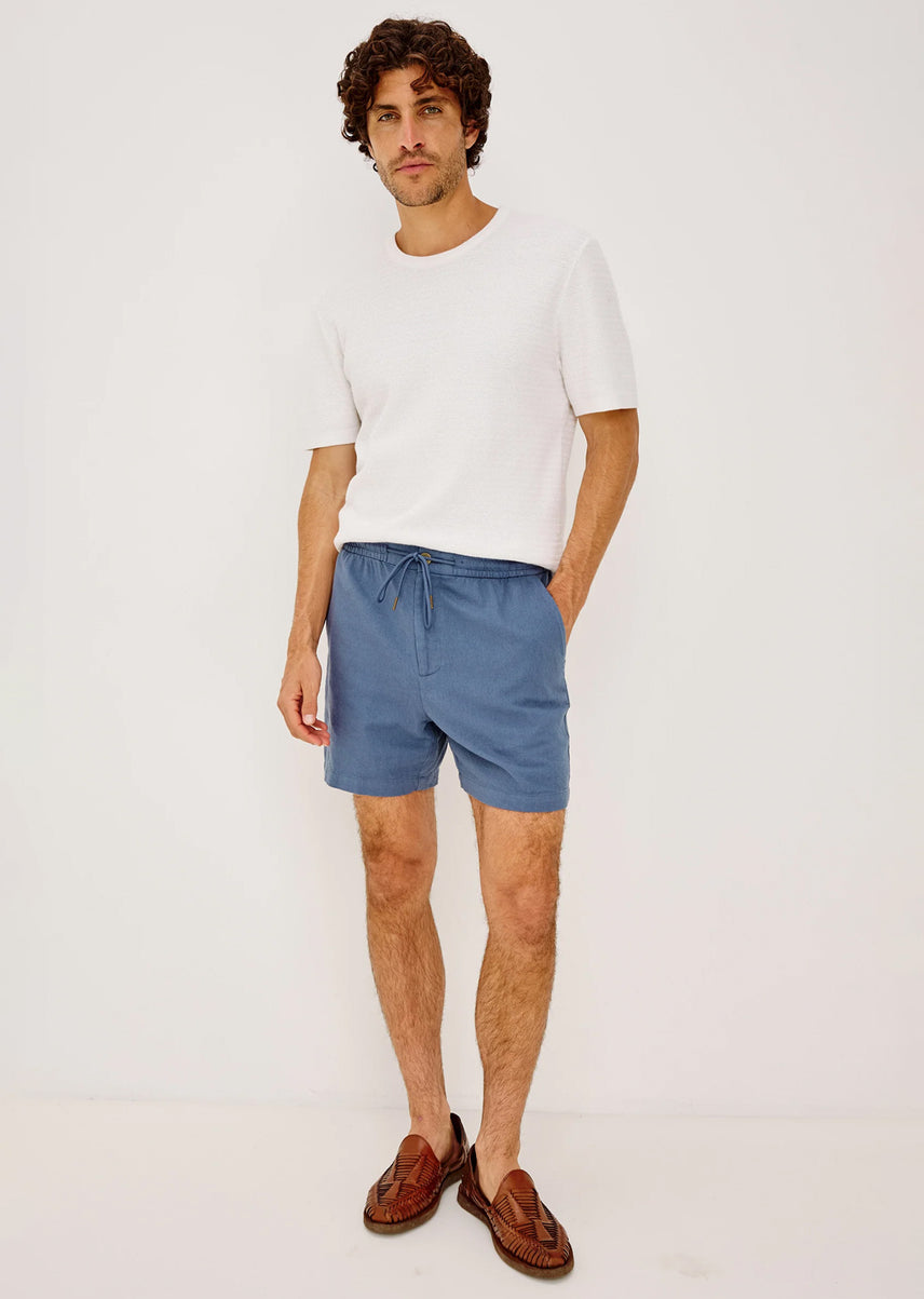 Man wearing a white t-shirt and blue shorts on a plain background