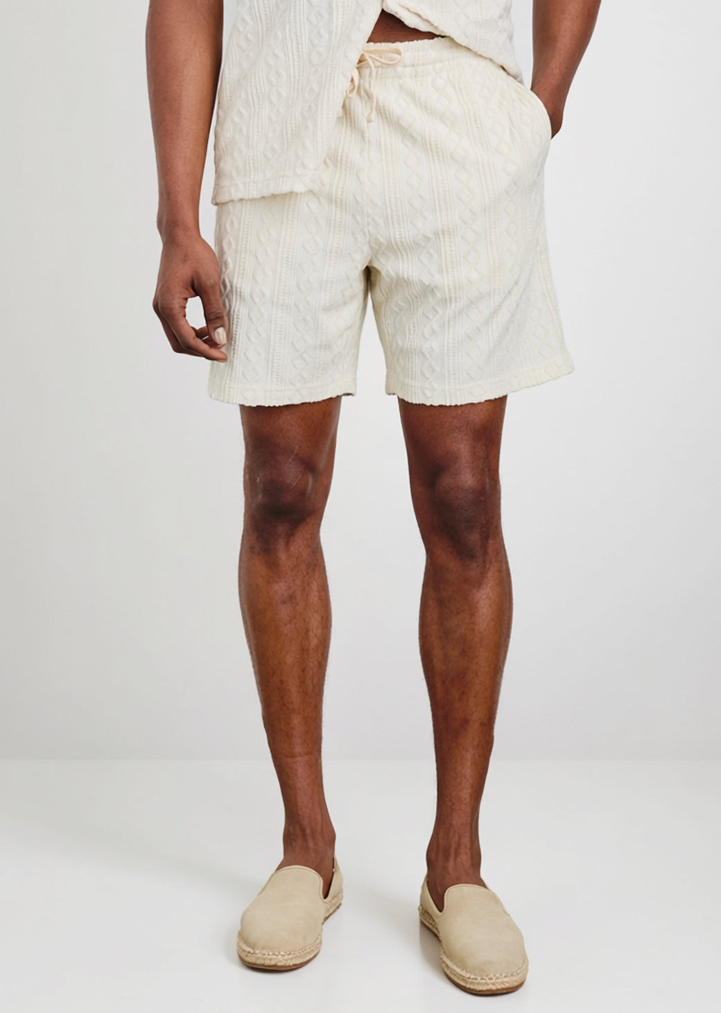 Person wearing light-colored shorts and shoes on a white background