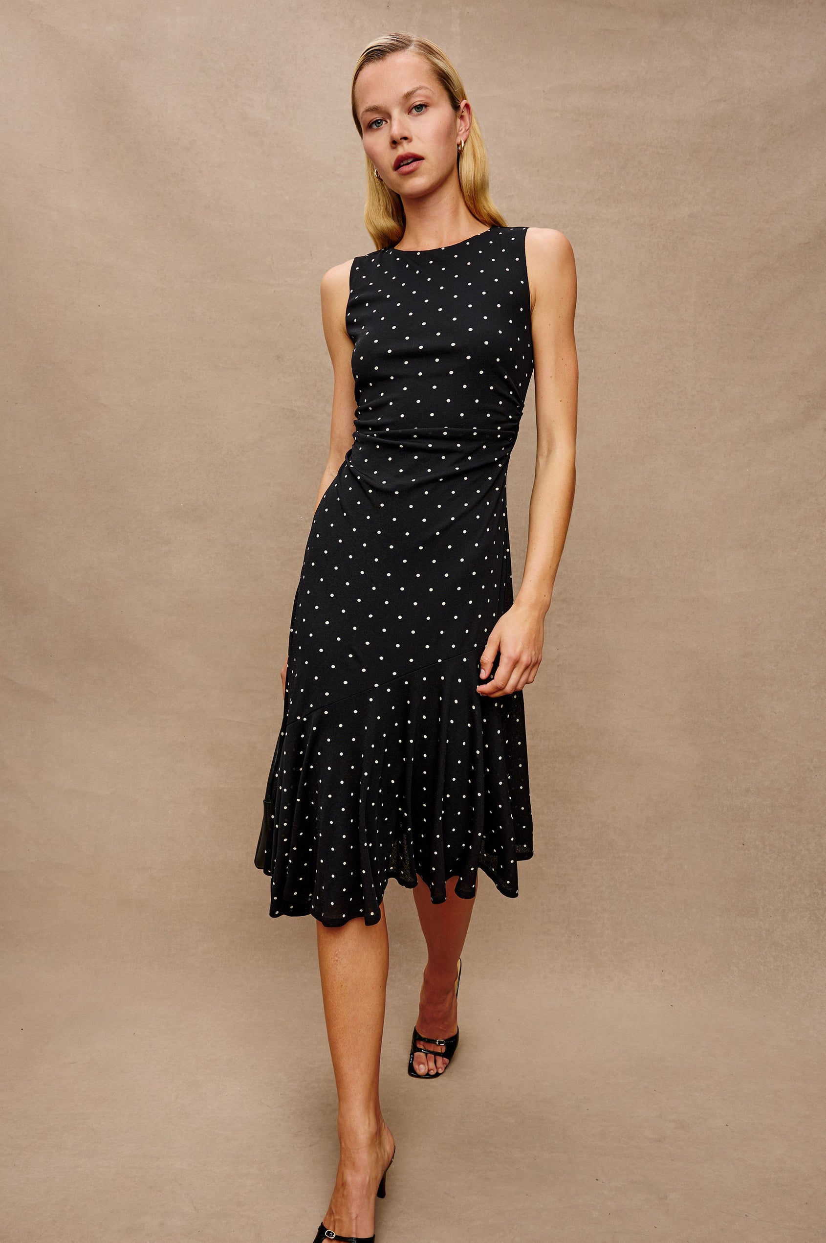 Daija Sleeveless Midi Dress with a Pleated Asymmetrical Hemline, and a Crew Neckline in Polka Dots Colorway - Front View Featured on Model
