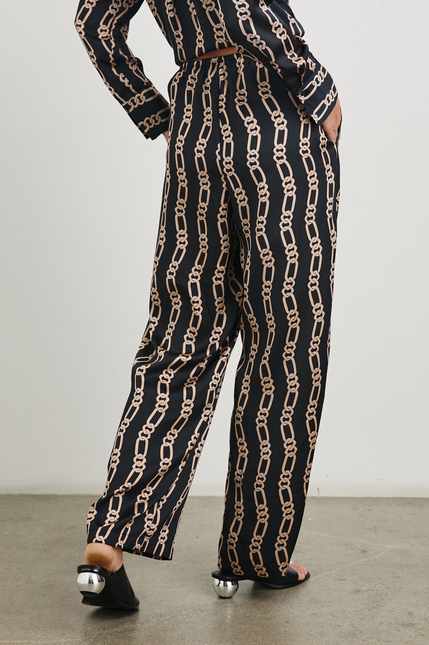 Damini Pants with a Drawstring Waist and Two Front Pockets in Black Gold Link Colorway, with Vertical rows of gold links on black - Back View Featured on Model