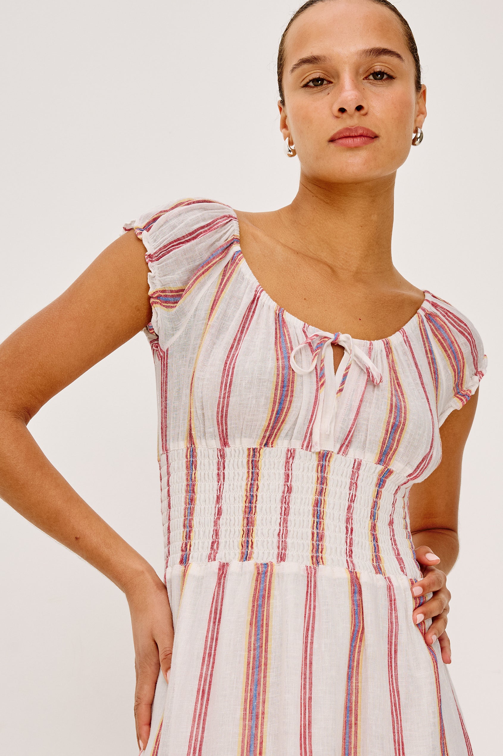 Daria Dress in Luxe Linen With Cap Sleeves, Scoop Neckline, Bust Ties, Smocked Waist, and Tiered Skirt in Primavera Stripe Colorway - Upper Body Front View Featured on Model