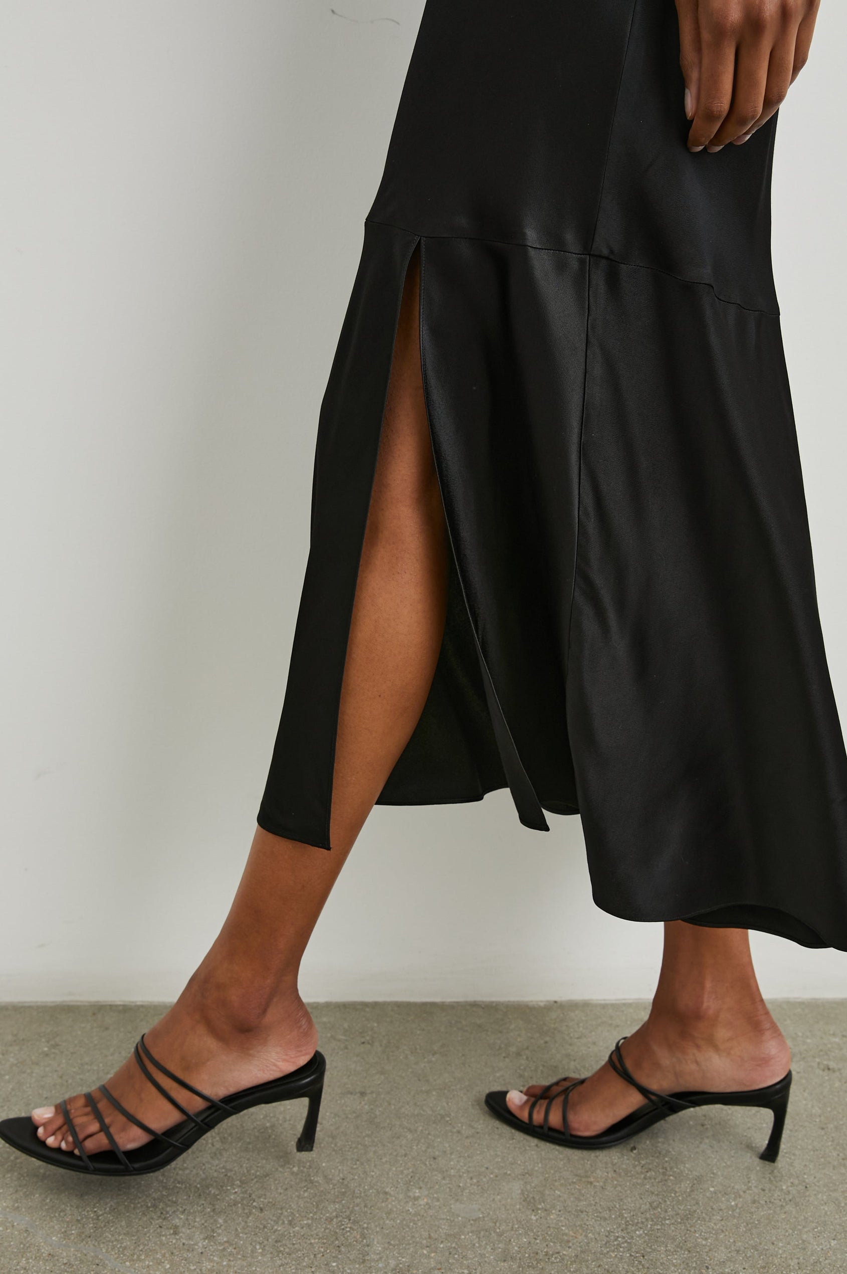 Dina Short-Sleeve Midi Dress with a Deep V Neck, Flutter Sleeves, and a Thigh Side Slit in Black Colorway - Side View Featured on Model