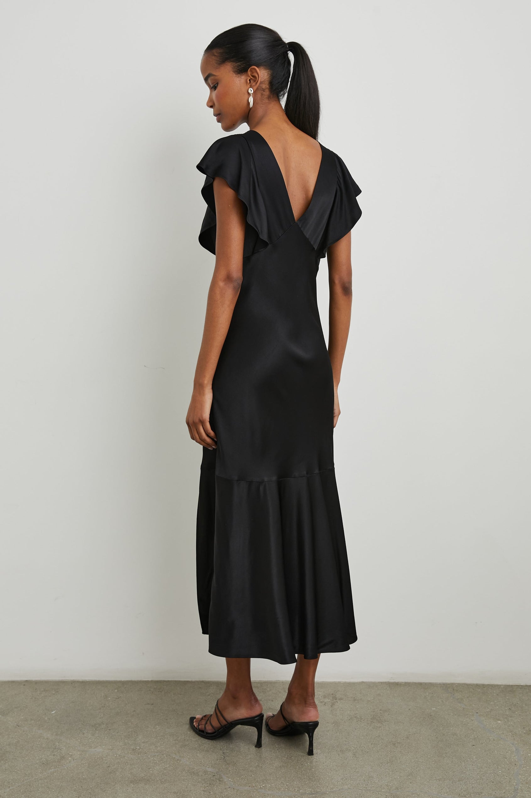 Dina Short-Sleeve Midi Dress with a Deep V Neck, Flutter Sleeves, and a Thigh Side Slit in Black Colorway - Back Full Body View Featured on Model