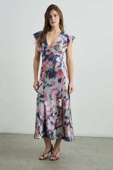 Dina Short-Sleeve Midi Dress with a Deep V Neck, Flutter Sleeves, and a Thigh Side Slit in Midnight Verbena Colorway, Flowers in Pinks, Blues, Oranges and white on Midnight - Front Full Body View Featured on Model