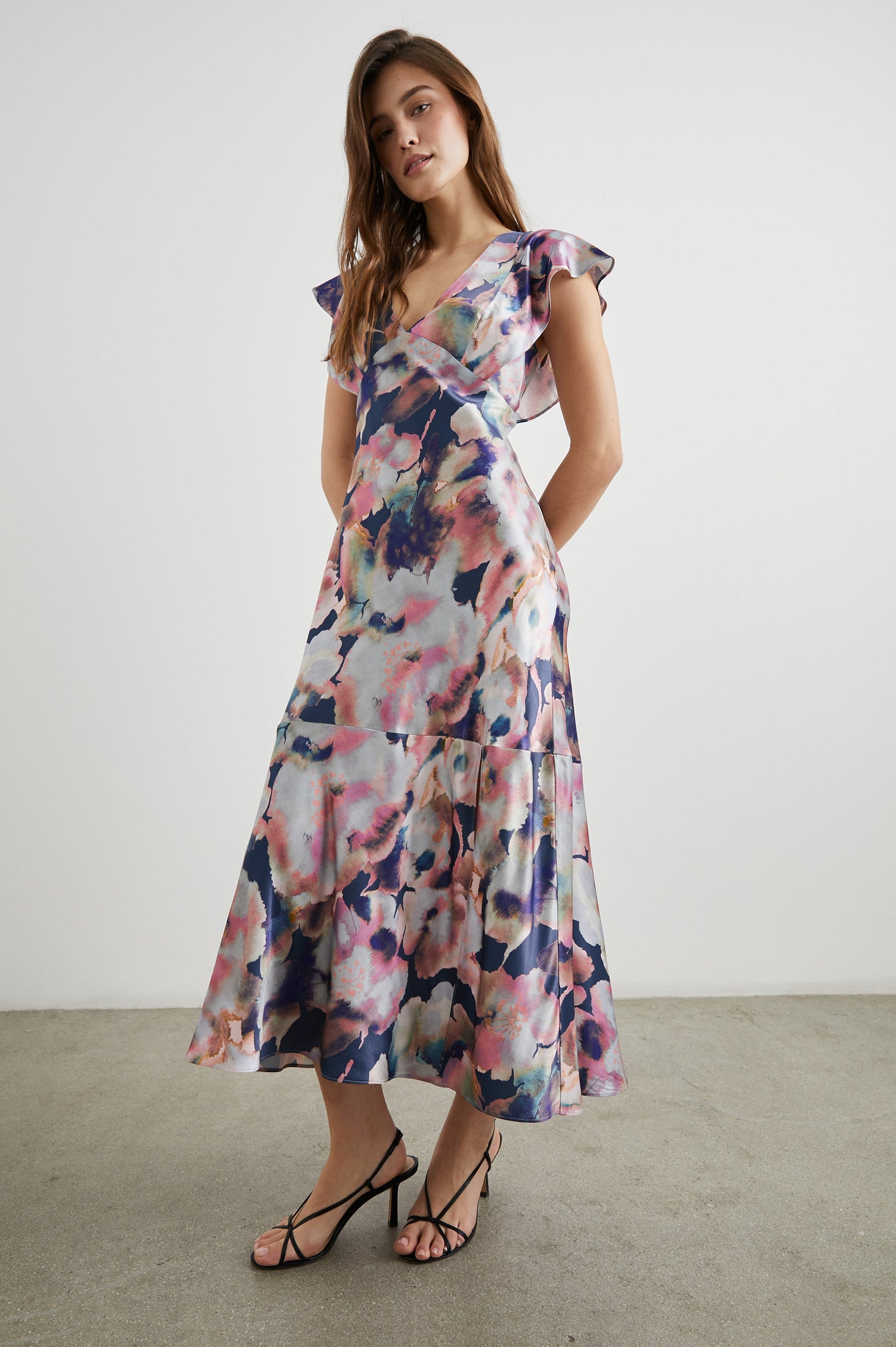 Dina Short-Sleeve Midi Dress with a Deep V Neck, Flutter Sleeves, and a Thigh Side Slit in Midnight Verbena Colorway, Flowers in Pinks, Blues, Oranges and white on Midnight - Front Full Body View Featured on Model