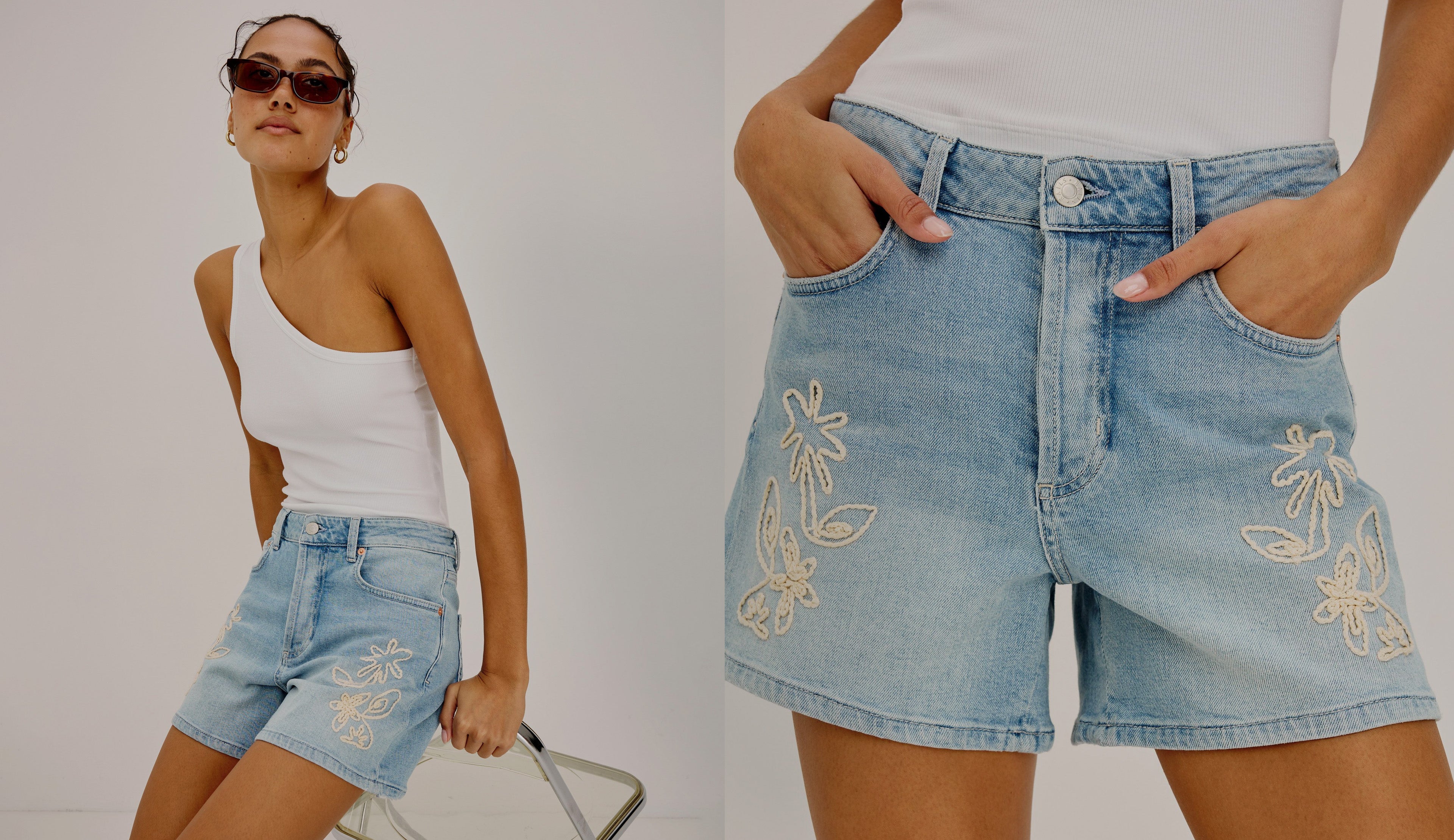 Woman wearing denim shorts with floral embroidery, standing against a plain background.