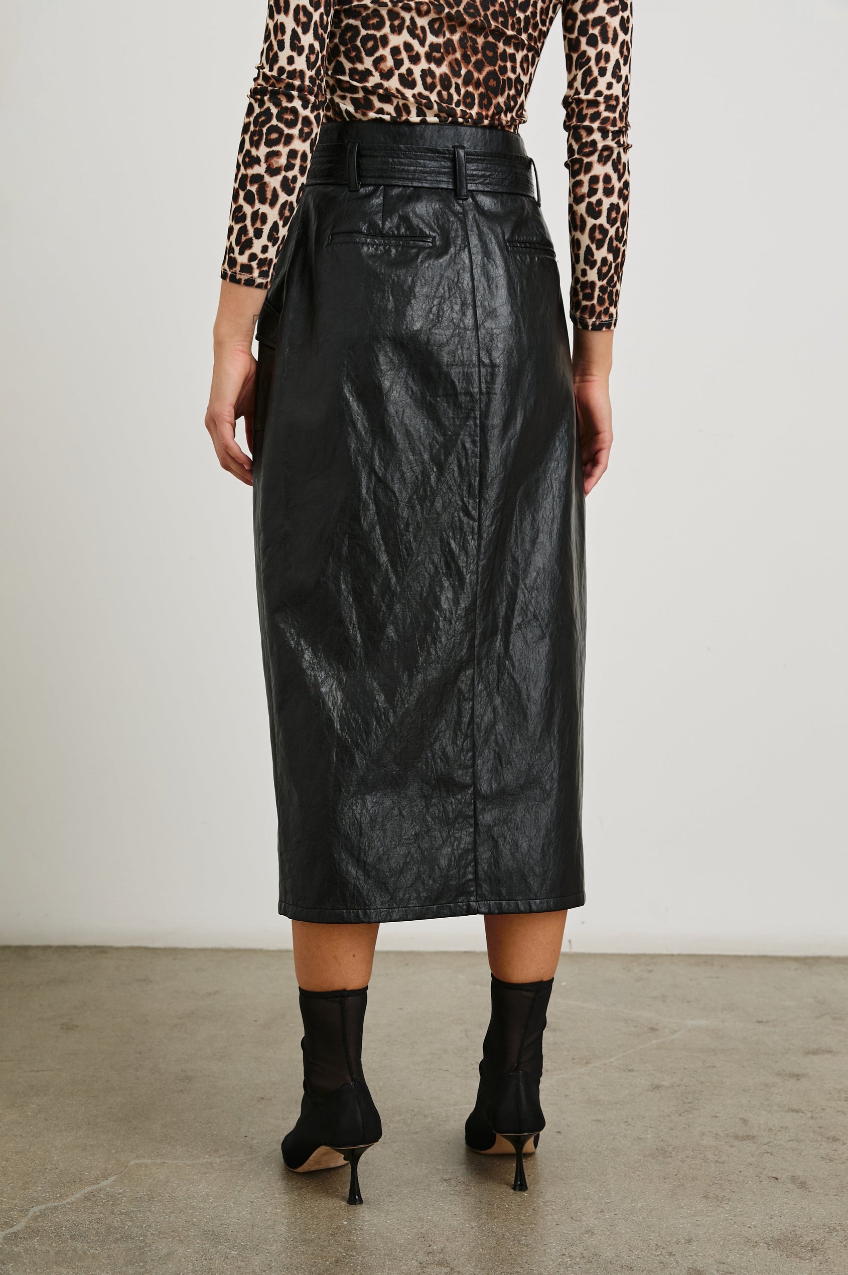 Edem Midi Skirt with a Tie Belt, a Center Slit, Four Button Closure at the Waist, Two Front Pockets Each Overlaid with a Button Flap Pocket and Two Back Welt Pockets in Black Colorway - Back View Featured on Model