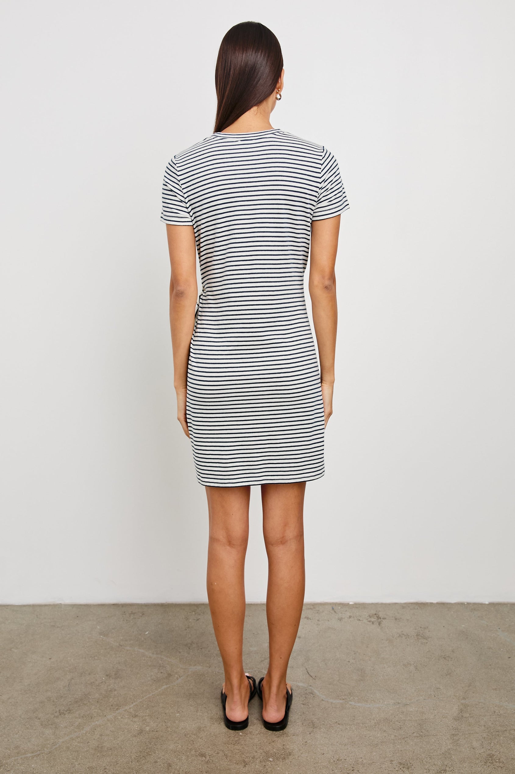 Edie Above-Knee Dress with Short Sleeves, Crew Neckline and Adjustable Wrap Tie At Waist in Ivory Navy Micro Stripe Colorway, Horizontal Stripes - Back View Featured on Model