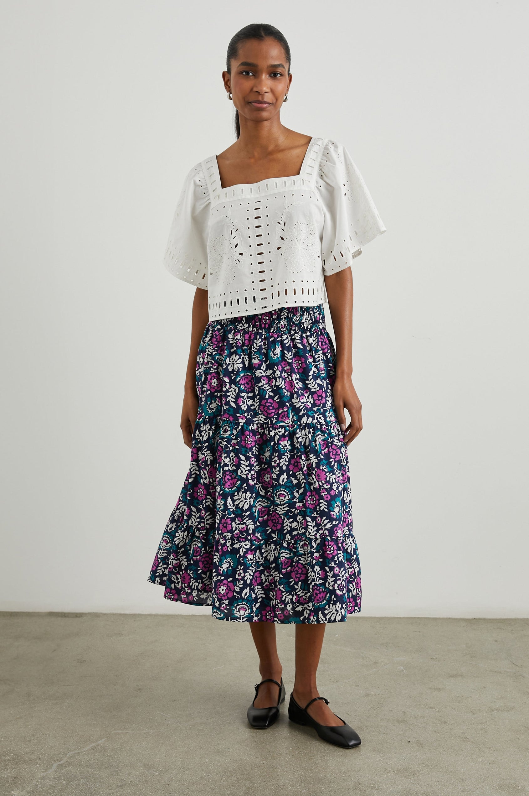 Edina Tiered Midi Skirt with Shirred High-Rise Waistline in Lilac Roses Colorway, with large flowers in purples, blues, and white - Front Full Body View Featured on Model