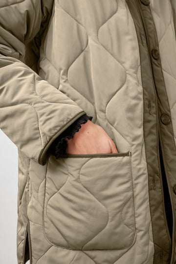 Elin Quilted Jacket with Button Closure, Side Slits, Low High Hem, Two Front Patch Pockets, and No Collar in Sage Colorway, with Darker Placket and Cuffs - Front View Featured on Model 