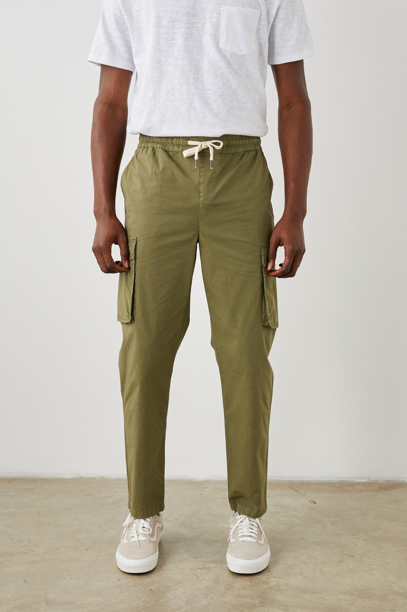 Emmerson Pants with a Drawstring Waist, Two Front Pockets, Two Side Flap Pockets and Two Back Welt Pockets in Olive Colorway - Front View Featured on Model