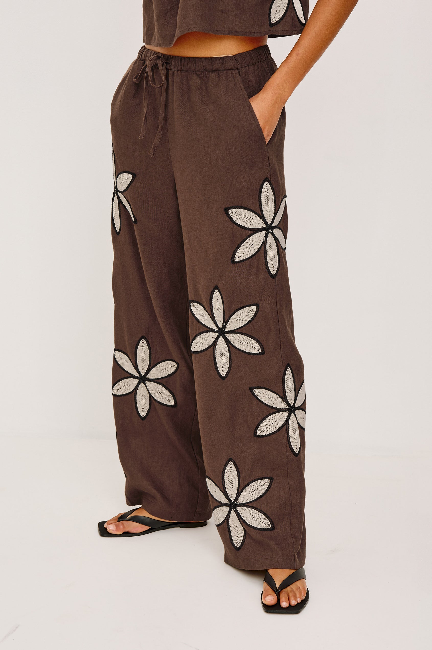 Emmie Straight Leg Pant in Unlined Linen With Adjustable Drawstring Waist Ties and Side Pockets in Cocoa Floral Embroidery Colorway — Lower Body Front View Featured on Model