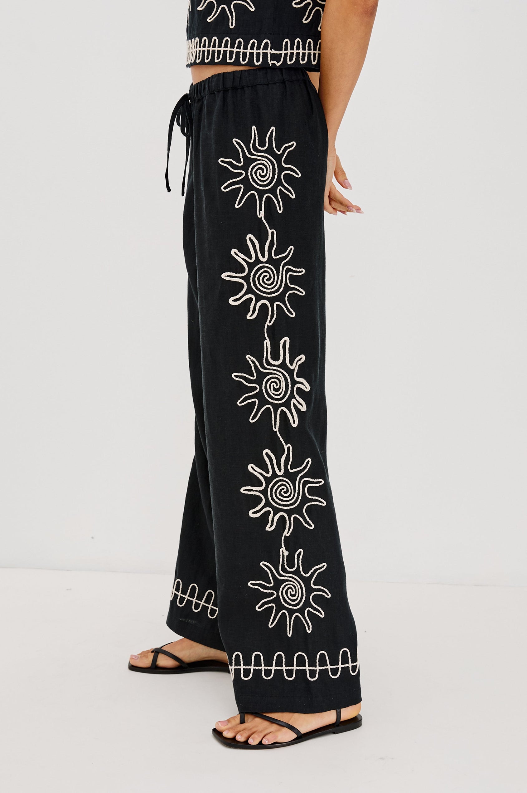 Emmie Straight Leg Pant with Adjustable Drawstring at Waist in White Contrast Sun Embroidery Colorway. Side View Shown on Model.