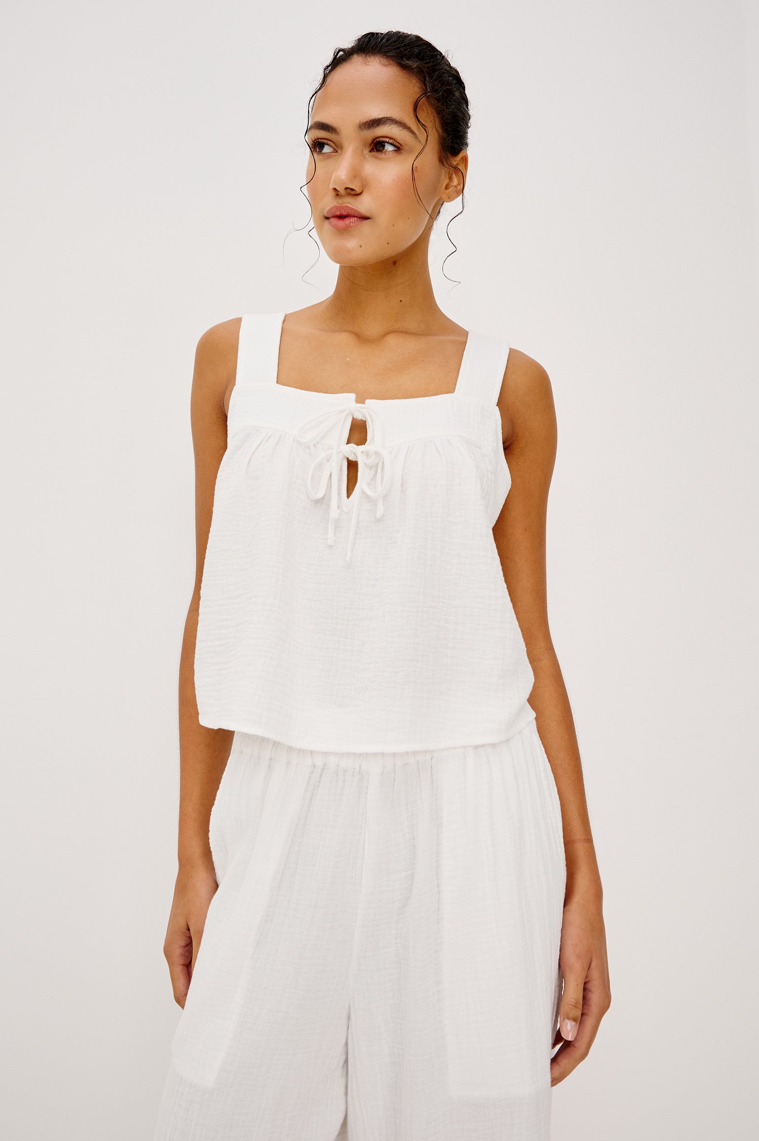 Enya Cropped Tank Top in Cotton Gauze With Square Neckline Wide Shoulder Straps Center Bust Keyhole With Adjustable Ties and Relaxed Fit in White Colorway - Upper Body Front View Featured on Model