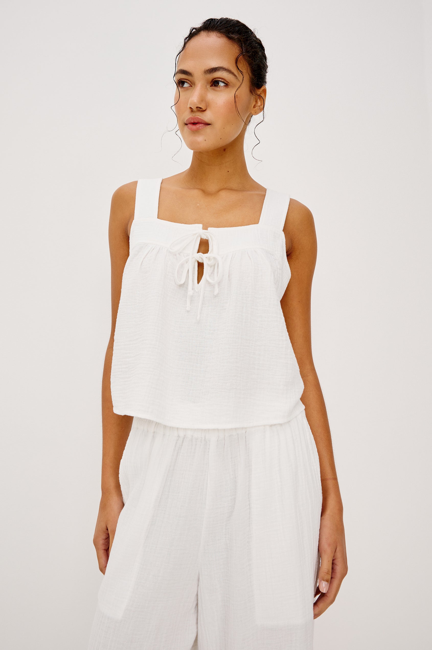 Enya Cropped Tank Top in Cotton Gauze With Square Neckline Wide Shoulder Straps Center Bust Keyhole With Adjustable Ties and Relaxed Fit in White Colorway - Upper Body Front View Featured on Model