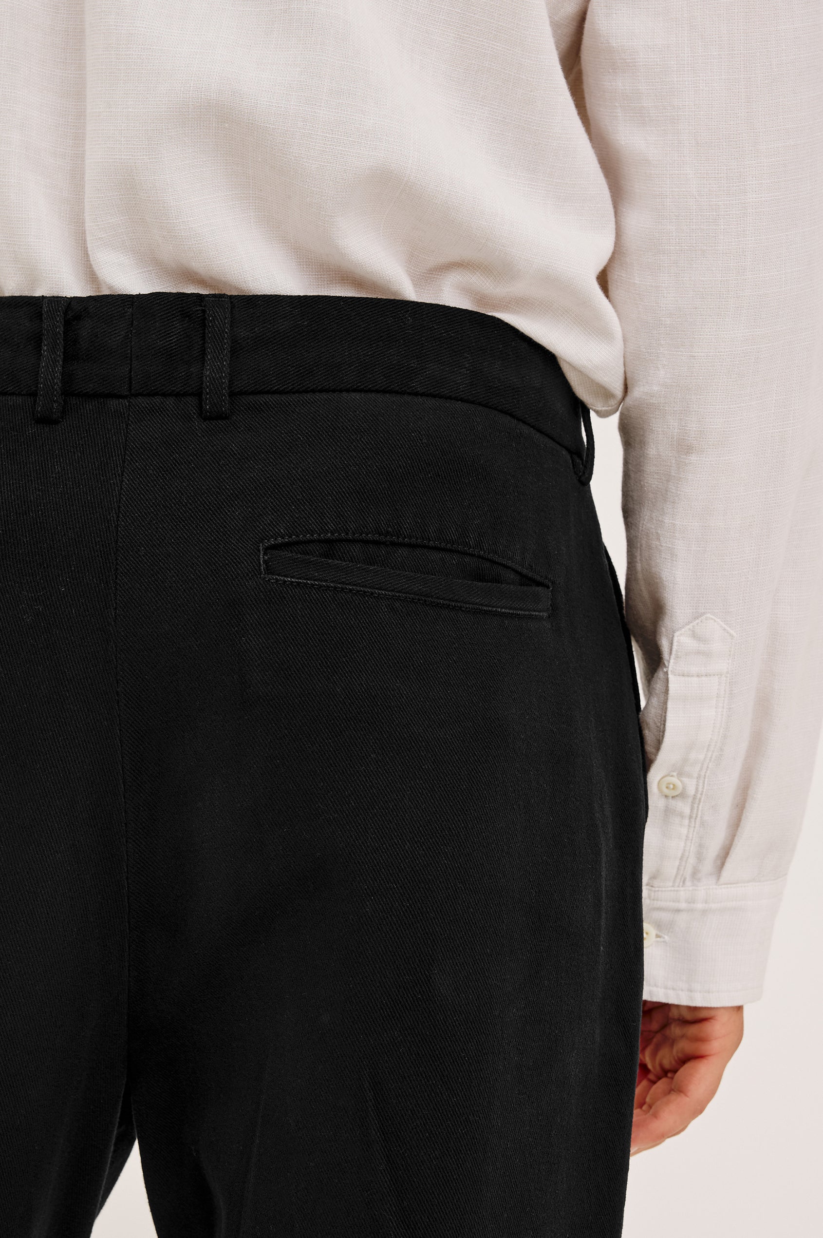Ezra Pant in Brushed Cotton Twill With Relaxed Fit, Single Front Pleats, Ankle-Length Hem, Zip Fly, Side Pockets, and Back Double-Welt Pockets in Black Colorway - Lower Body Back View Featured on Model